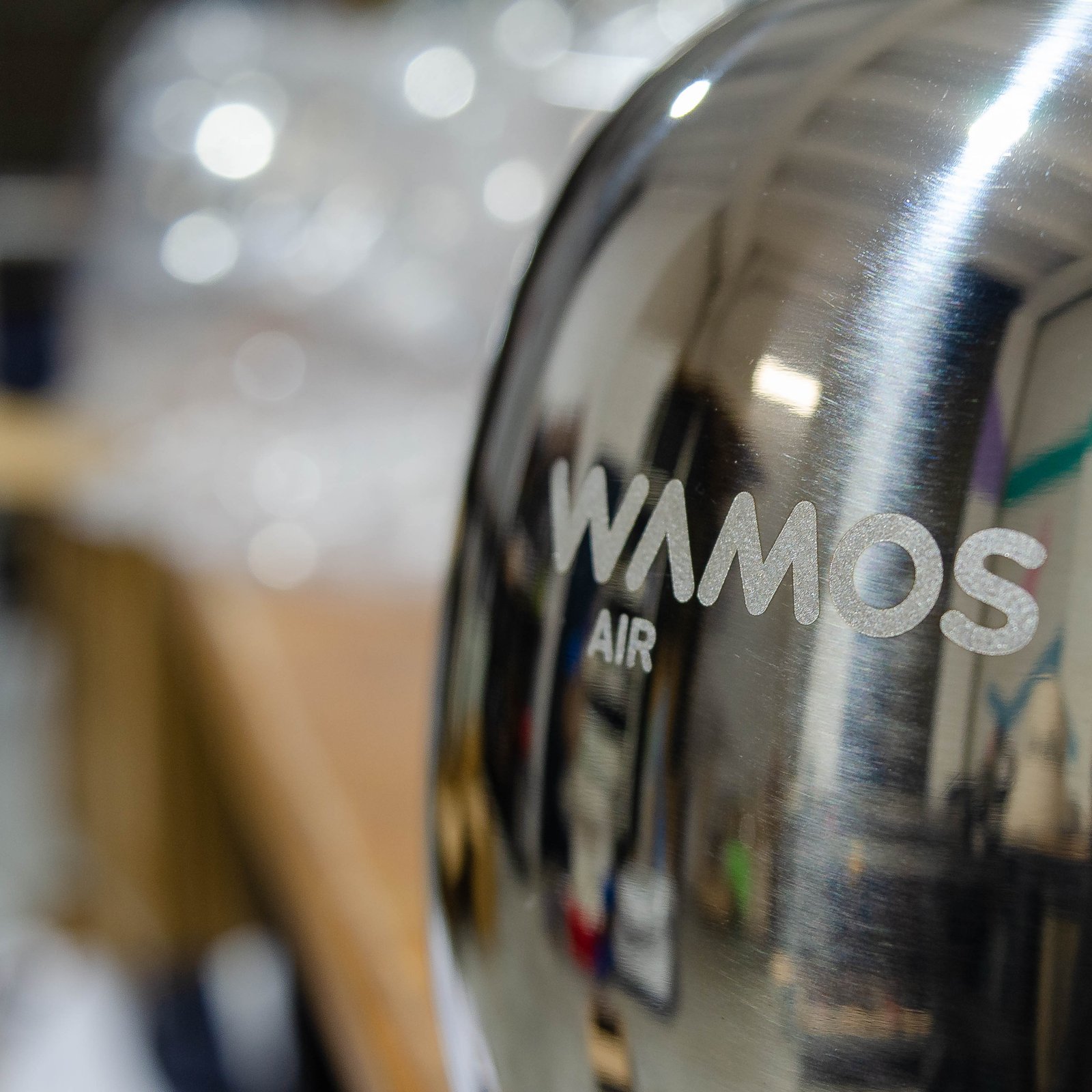 Detalle del marcaje láser del logo WAMOS AIR sobre cafetera de acero inoxidable espejo