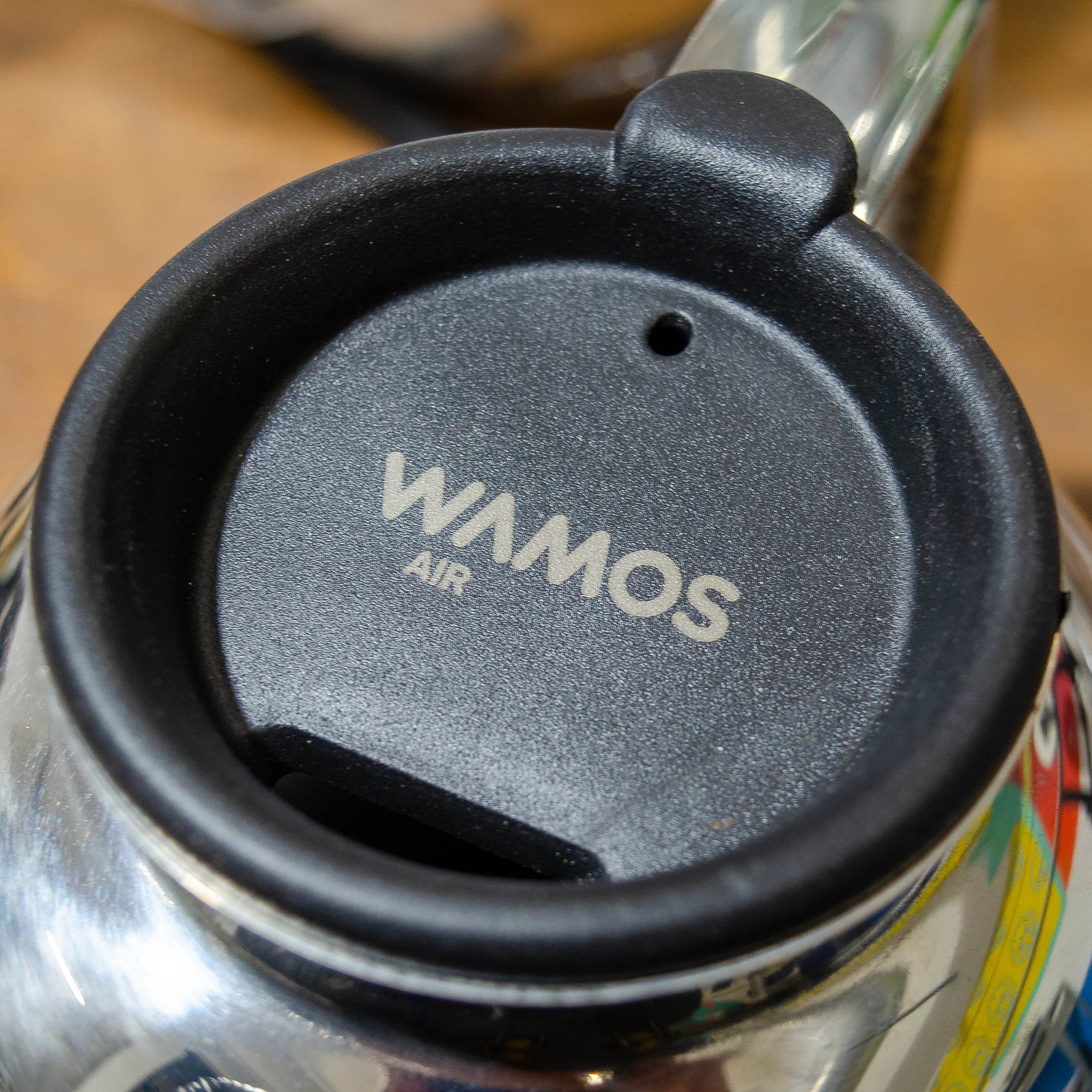Tapa de polipropileno negro con marcaje láser del logo WAMOS AIR, detalle de cafetera