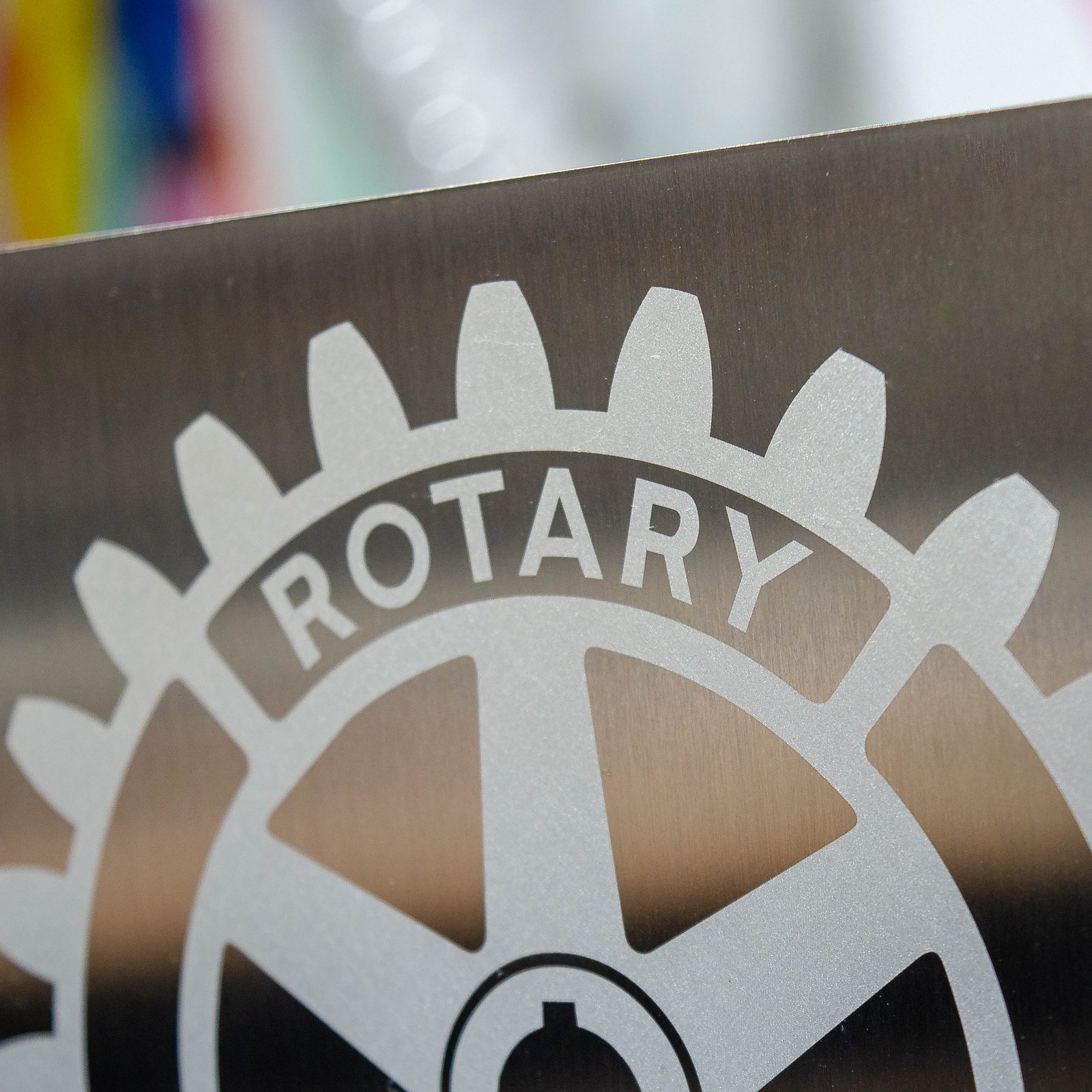 Detalle del logotipo de Rotary International marcado con láser sobre acero inoxidable cepillado